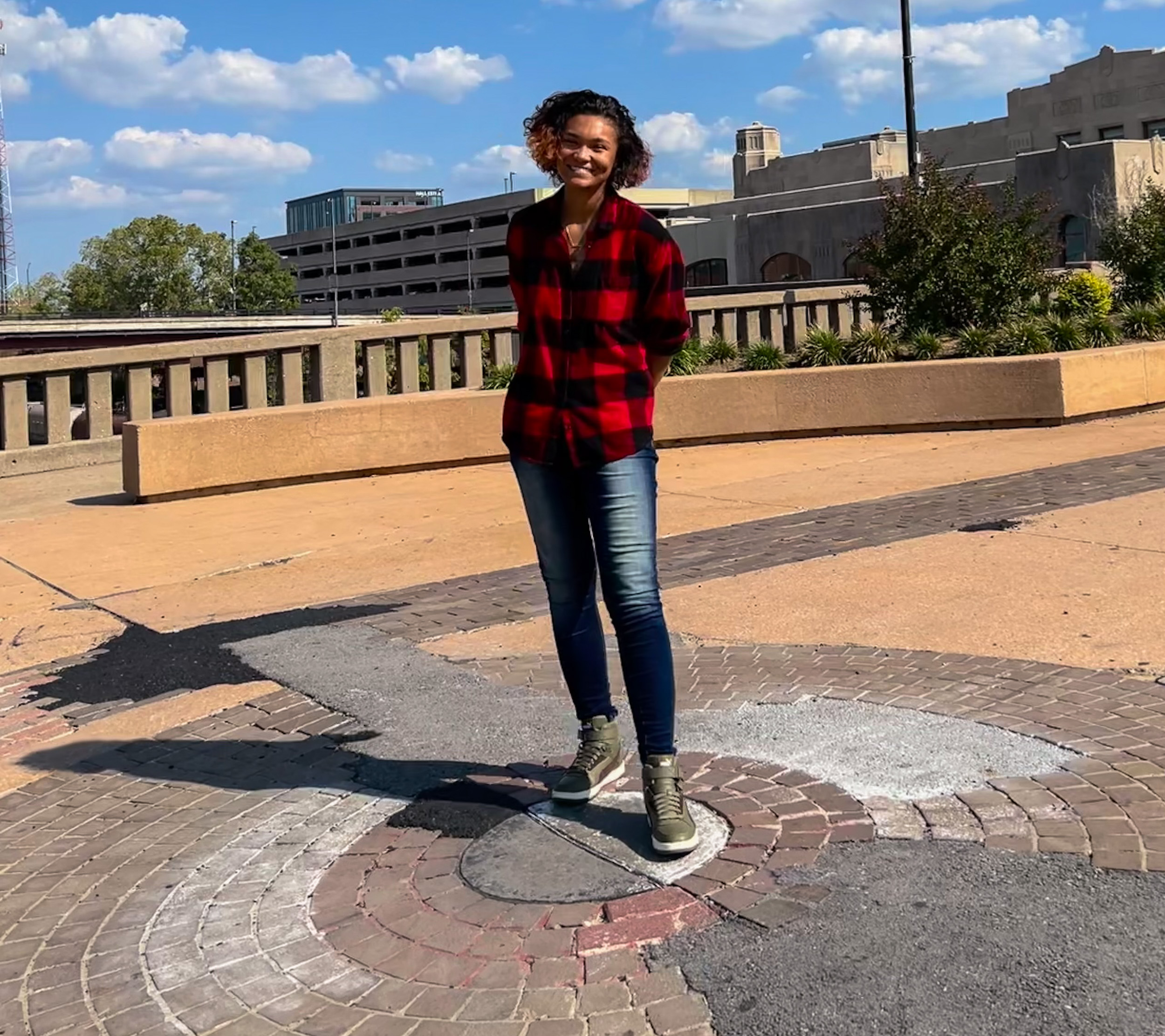 Person stands on concrete smiling.